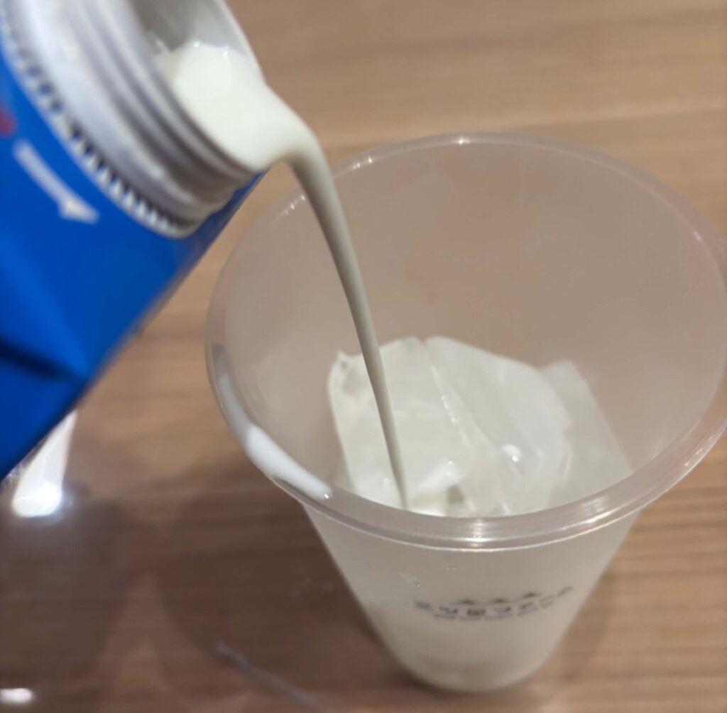 温めたタピオカを氷入りのコップに牛乳を注ぐ