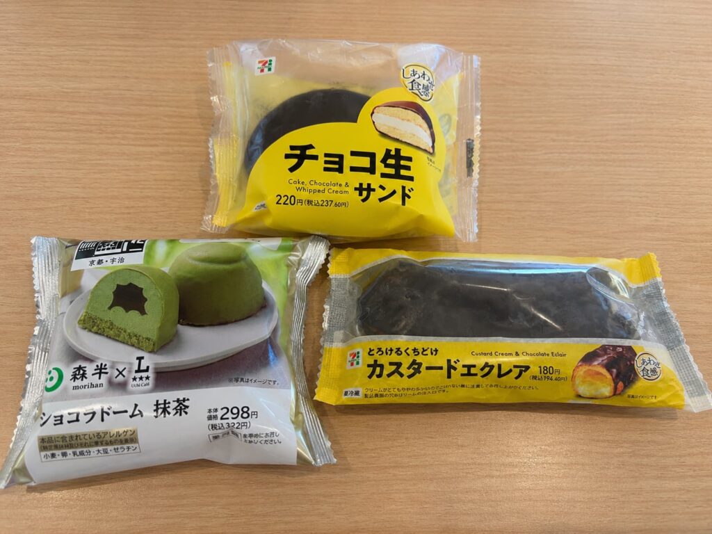 セブンイレブンのチョコ生サンド、カスタードエクレア、ローソンのショコラドーム抹茶のコンビニスイーツを並べた様子