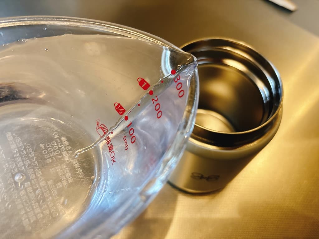 スープジャーに水を入れてどのくらい入るか調べる様子