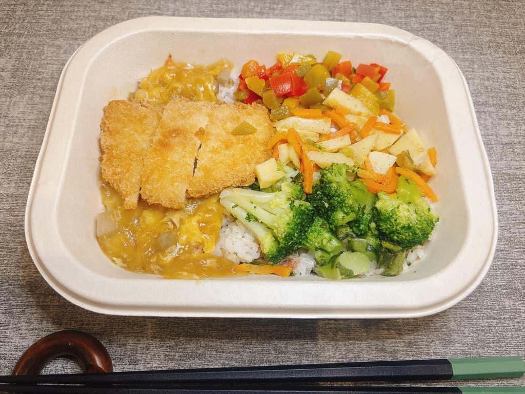 仕切りのない容器に、おかずとまぜご飯が並んだ盛り付け